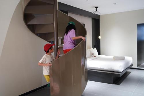 two children are walking up a staircase to a bunk bed at Rest Collection RedHouse Melaka in Melaka