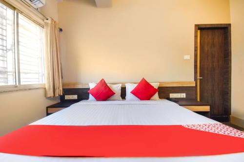 a bedroom with a large bed with red pillows at Hotel O Mourigram Near Andul Rd in Kolkata