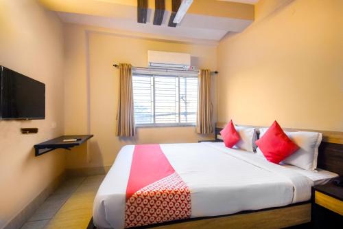 a bedroom with a large bed with red pillows at Hotel O Mourigram Near Andul Rd in Kolkata