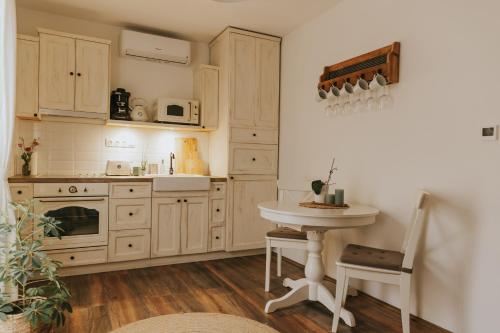 a kitchen with wooden cabinets and a table and a sink at Neidhardt Vendégház in Bóly