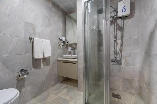 a bathroom with a shower and a toilet and a sink at Echinus Lara Hotel in Antalya
