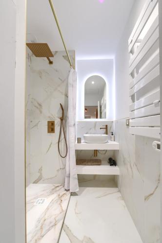 une salle de bain blanche avec un lavabo et un miroir dans l'établissement Appartement prestigieux à 5 minutes à pied de la gare et du palais de festival, à Cannes