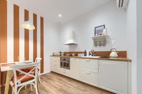 une cuisine avec des placards blancs et une table avec une chaise dans l'établissement Appartement prestigieux à 5 minutes à pied de la gare et du palais de festival, à Cannes