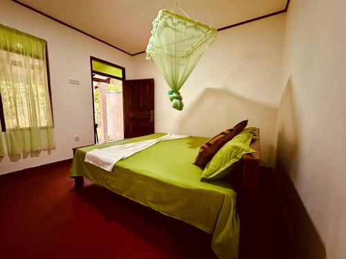 a bedroom with a green bed with an umbrella on the wall at Coco Cabana Hikkaduwa in Hikkaduwa