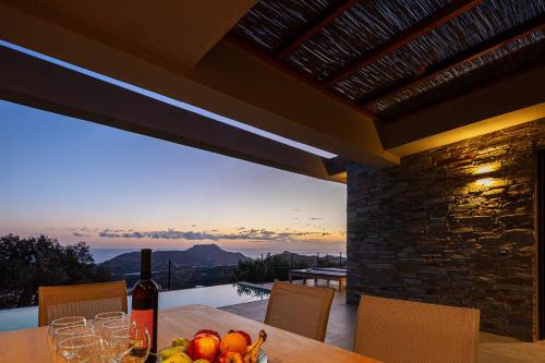 a table with a bottle of wine and a bowl of fruit at Villa Oniriko in Marioú