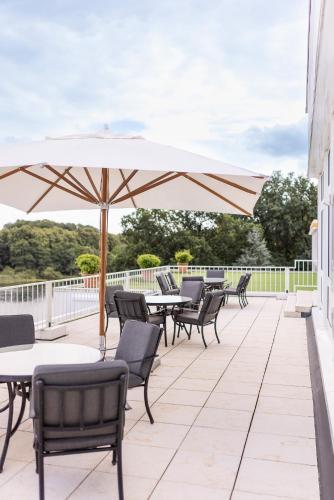 a patio with tables and chairs and an umbrella at Vitalia Seehotel in Bad Segeberg