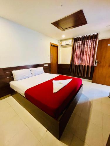 a bedroom with a large bed with a red blanket at Meridin Regency in Ernakulam