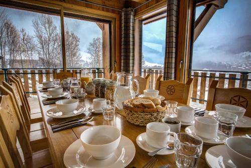 une table avec des assiettes et des tasses ainsi qu'un panier de pain dans l'établissement Chalet L'abelard By Birch Stays, à Morzine