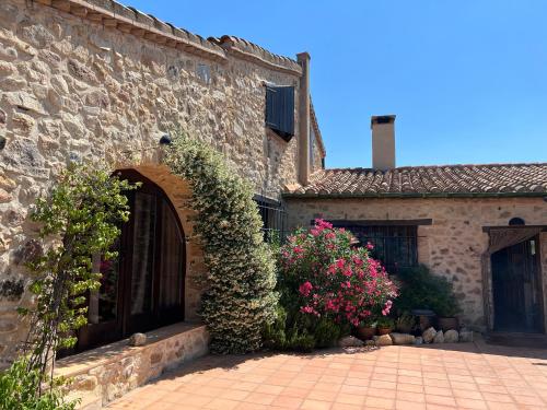 a stone building with a door and some flowers at Mas Ambras in Agullana