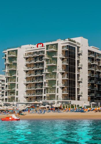 a large building on the beach with a boat in the water at Royal Central Hotel and Resort The Palm in Dubai