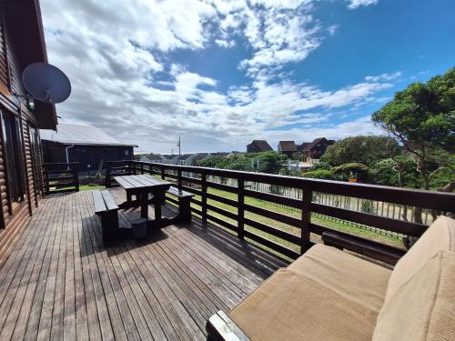 a wooden deck with a bench and a table on it at Nine Waves Beach House in Port Alfred