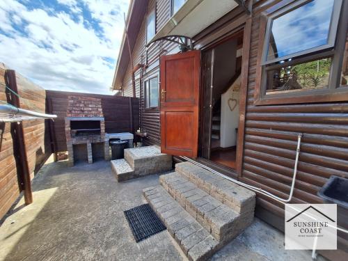 a porch of a house with stairs and a fireplace at Nine Waves Beach House in Port Alfred