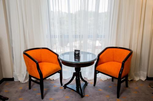 two orange chairs and a glass table in front of a window at Carnaval Hotel Casino in Encarnación