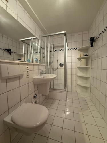 a white bathroom with a toilet and a sink at Ferienwohnungen Alte Schmiede 9 in Norderney