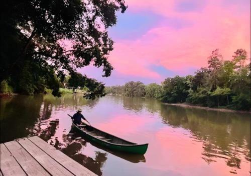 a man in a canoe on a river near a dock at Secluded Riverside Oasis Private Deck Dock in Baton Rouge