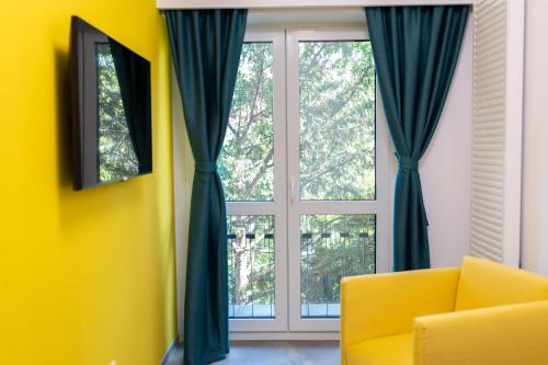 a living room with a yellow chair and a window at Johann Strauss Hotel in Bucharest