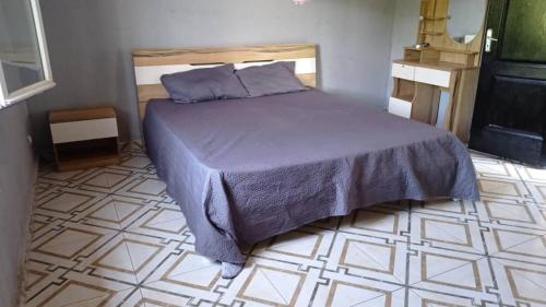 a bedroom with a bed and a tiled floor at La Villa Émeraude in Mbachilé