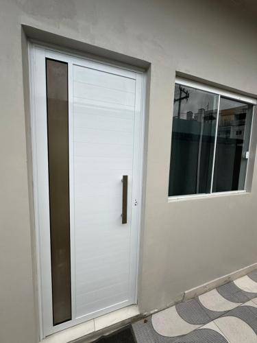 a white door with a window on a building at Marcial Guest House - À 2 Quadras do Mar in Matinhos