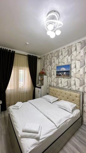 a bedroom with a large white bed with a stone wall at Shosh Garden Family Resort in Chorwoq