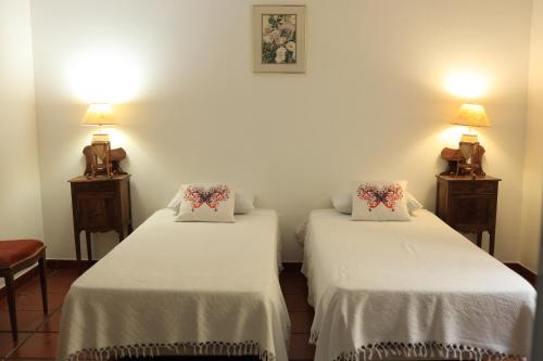 a room with two beds with white sheets and two lamps at Nanna's Country Home in Feteira Grande