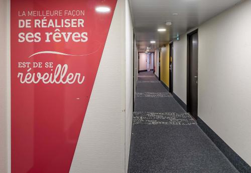 a hallway with a red wall with writing on it at B&B HOTEL Bordeaux Le Haillan 3 étoiles in Le Haillan