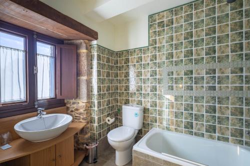 a bathroom with a toilet and a sink and a tub at Casa Souto De Abajo in Santiso