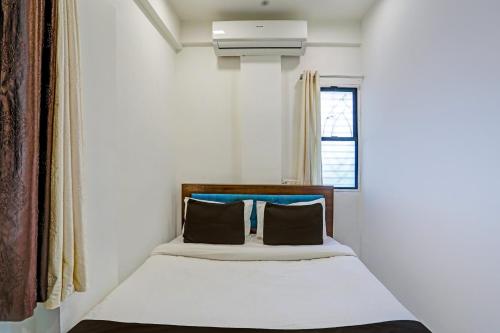 a small bedroom with a bed with a window at Super Collection O Besa Square Nagpur Formerly Yuva Inn in Nagpur