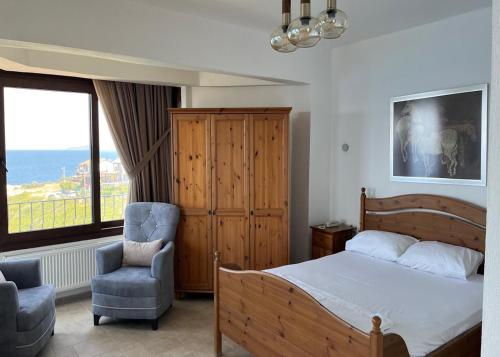 a bedroom with a bed and a chair and a window at Nergis Hotel in Karaburun