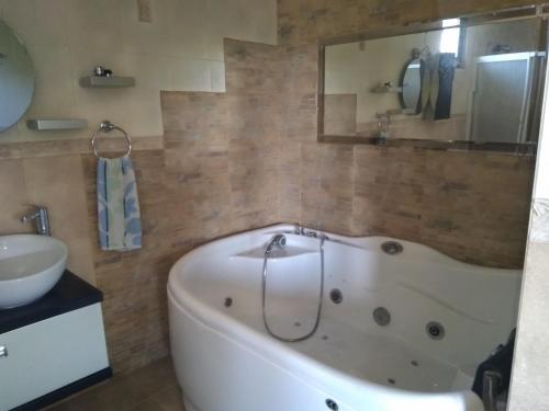 a bath tub in a bathroom with a sink and a mirror at Guest House Poli in Levski