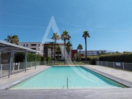 une piscine avec des palmiers et un bâtiment dans l'établissement 3 CHAMBRES TOUT CONFORT EN BORD DE MER, à Sète