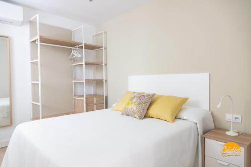 a white bedroom with a white bed and shelves at Villalobos by Cadiz Time in Cádiz