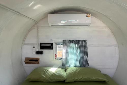 a bed in a small room with a window at Kua Car Camp in Lampang