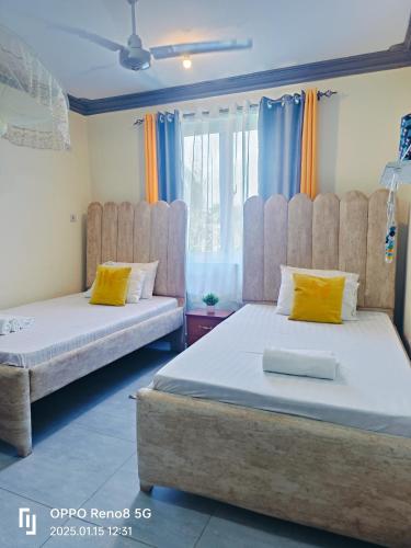a bedroom with two beds with yellow and blue curtains at LES INTERNATIONAL in Mombasa