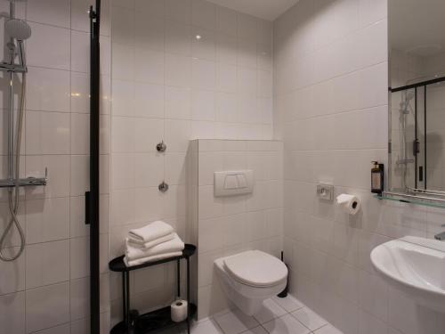 a white bathroom with a toilet and a sink at Hotel Atrium in Kraków