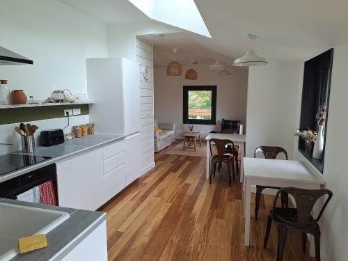 a kitchen with white cabinets and a dining room at Le Clos du Palastre, à 10 mn de Vannes in Plescop