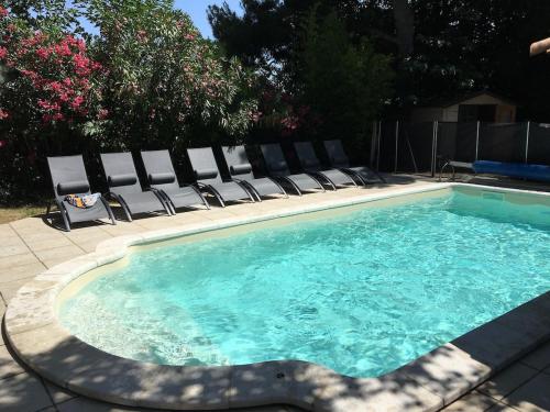 une piscine avec des chaises longues et une piscine dans l'établissement L'Oustalou, à Béziers