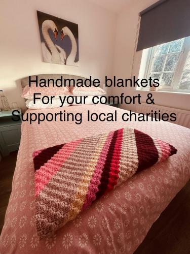 a bed with a crochet blanket and a pillow on it at Chez Ana in Saxmundham