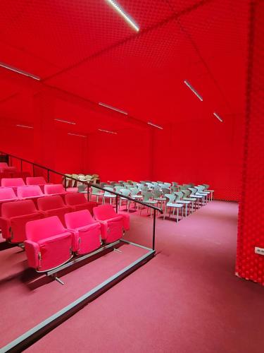 an empty lecture hall with red chairs and tables at Hotel Mio City in Kula