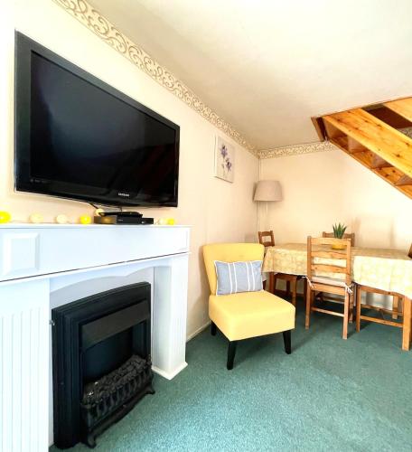 a living room with a fireplace with a flat screen tv at Annie's Cottage - 3 miles from the iconic Minack Theatre in Saint Buryan