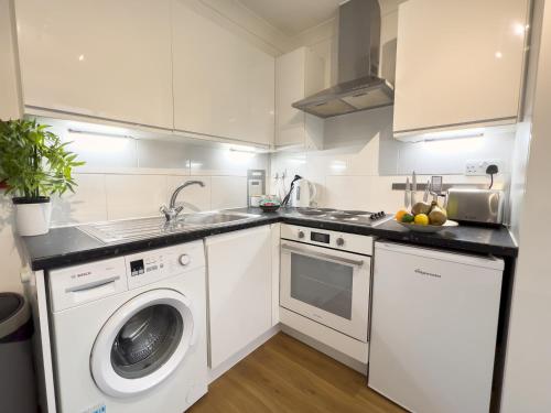 a white kitchen with a sink and a washing machine at Pass the Keys Amersham Station Road Studio in Amersham