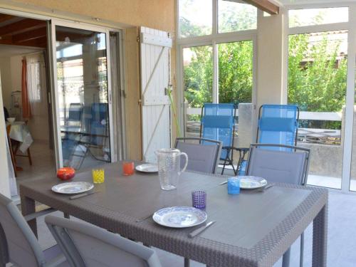 - une table et des chaises gris dans une chambre avec fenêtres dans l'établissement Maison en bord de mer, climatisée, terrasse, véranda, parking privé, 200m des plages, 6 couchages - FR-1-229B-21, à Narbonne