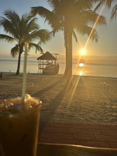 a drink sitting on a table on a beach with palm trees at Maya Beach Hotel in Maya Beach