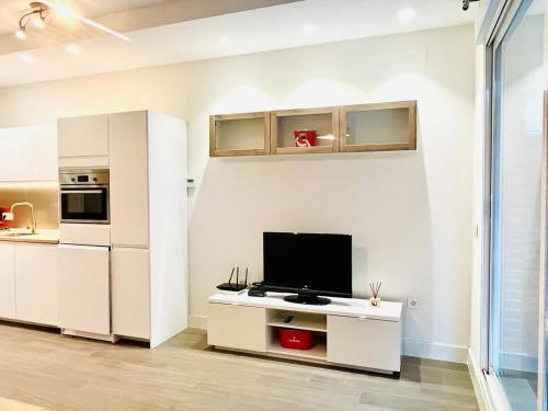 une cuisine avec des armoires blanches et une télévision à écran plat dans l'établissement Central and spacious apartment-Historic Center, à Malaga