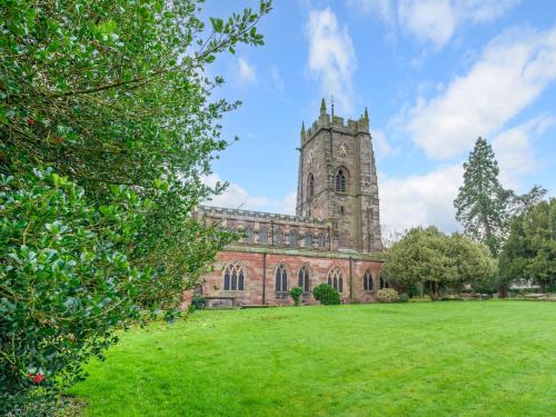 an old church with a tower on a grass field at Pass the Keys Stay in the Original Home of the Gingerbread Man! in Market Drayton