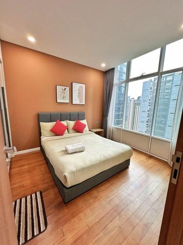 a bedroom with a bed with red pillows and a large window at Sky Suites KLCC by KD Luxury Suites in Kuala Lumpur