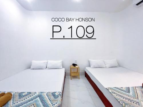 two beds in a room with a sign on the wall at Coco Bay Hon Son in Lai Sơn