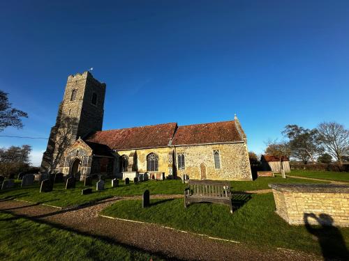 an old church with a bench in front of it at Chez Ana in Saxmundham
