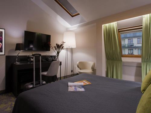 a room with a bed and a desk and a television at Hotel Atrium in Kraków