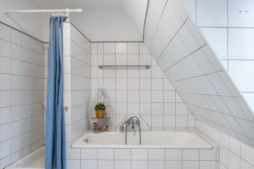 a bathroom with a bath tub with a blue shower curtain at Ferienwohnung Altstadtblick in Alsfeld