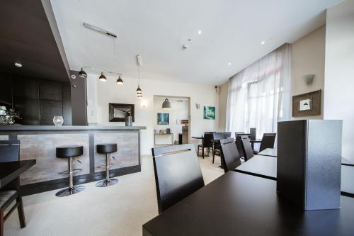 a dining room with tables and chairs and a bar at LOGIS HOTEL - Le Petit Bellon in Senlis